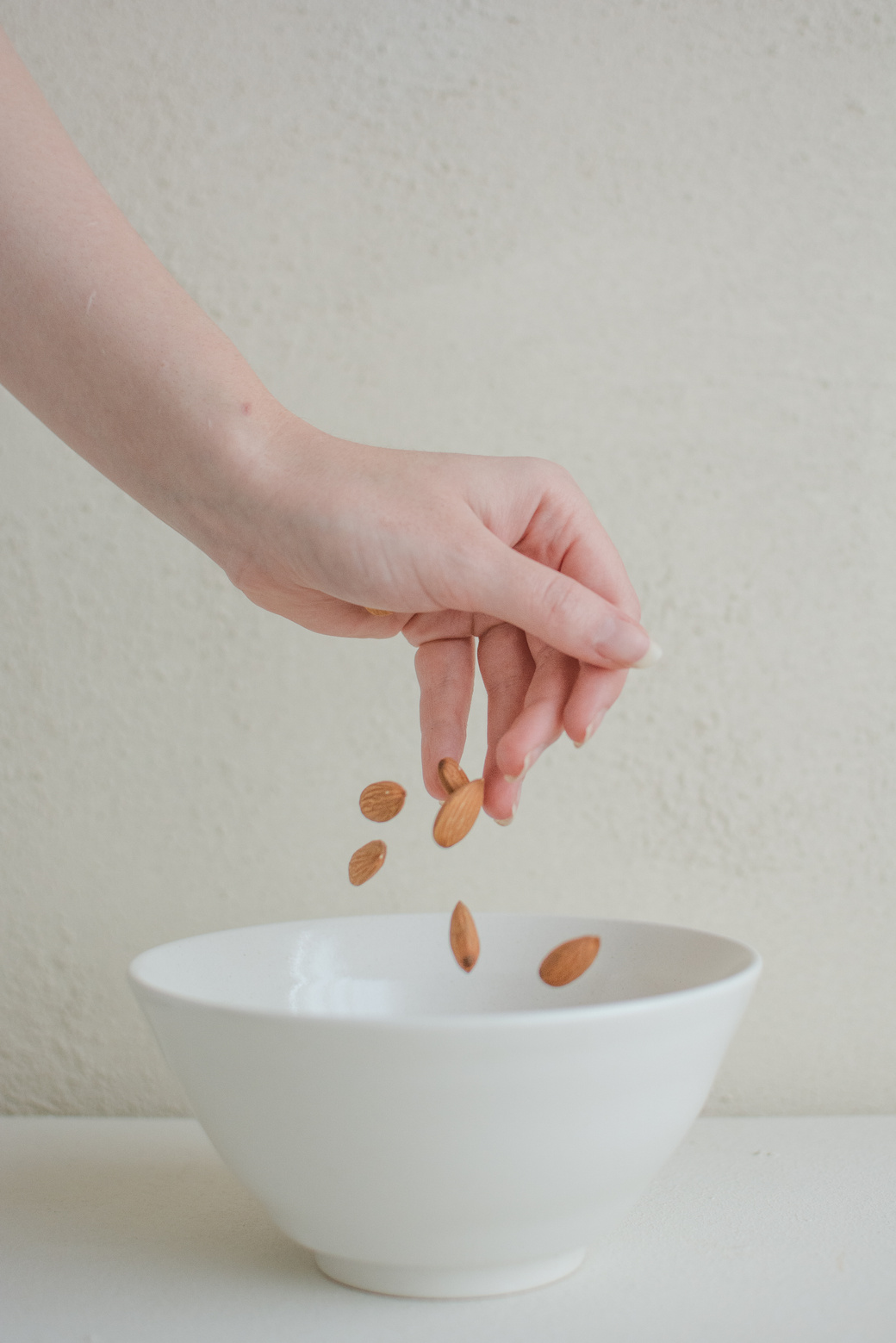 Person's Hand Putting Almonds in a Bowl